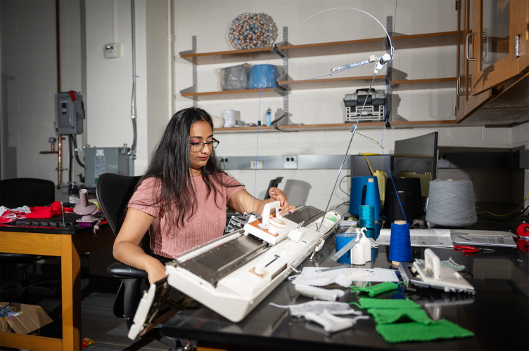 Krishma Singal sitting at a knitting machine